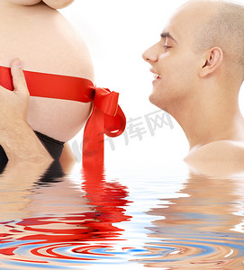 水红丝带摄影照片_骄傲的父亲和肚子上挂着红丝带的水