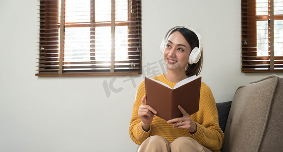 在家放松的微笑女孩，她正在用智能手机播放音乐，戴着白色耳机