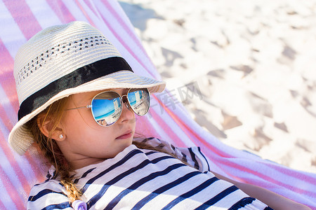 海边躺摄影照片_躺在沙滩躺椅上的小可爱女孩的肖像