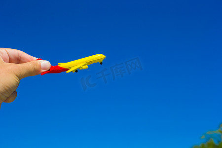 蓝天背景下女性手中的小飞机
