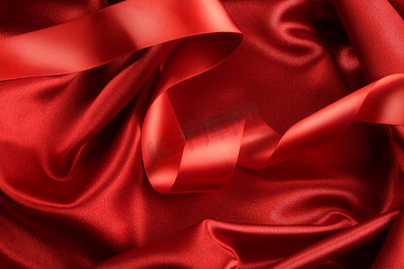 红色褶皱摄影照片_带丝带的深红色缎布