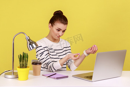 女工坐在工作场所，向进行视频通话的笔记本电脑屏幕展示金钱手势。