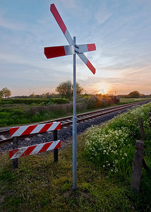 铁轨风景摄影照片_乡村场景中带柔和日落和交通标志的铁轨