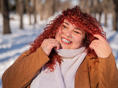 一个微笑的胖乎乎的红发女人在冬天散步的画像。