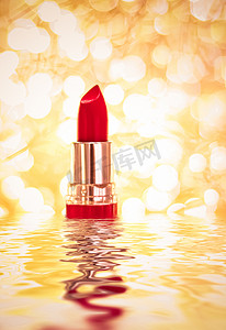 广告背景金色摄影照片_金色背景上的红色唇膏、化妆品和化妆品