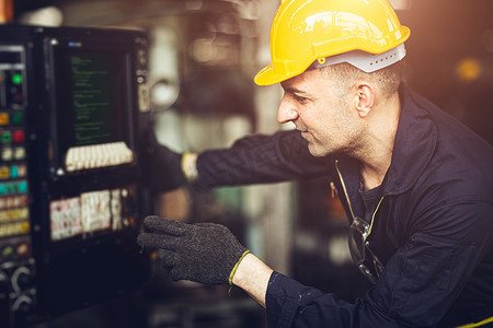 机器控制面板上的专业劳工工程师监视器按下用于编程 CNC 加工的按钮。