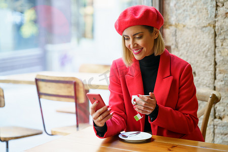 在咖啡馆里喝茶浏览智能手机的高兴女人