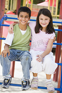 坐在游乐场结构上微笑的两个幼儿
