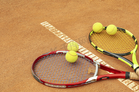 游戏娱乐摄影照片_红土球场上带网球的网球拍