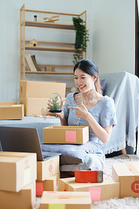 独立产品摄影照片_在做出购买决定之前，使用电脑向客户展示产品的独立年轻亚洲女性在线卖家的小型企业创业者。