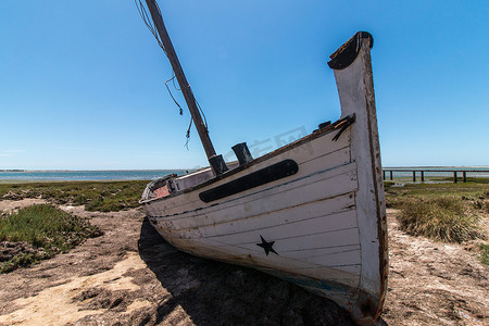 蓝色放射摄影照片_Ria Formosa 沼泽地沙丘植被上的弃船