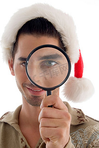 圣诞帽服装摄影照片_拿着放大镜和戴着圣诞帽的男性
