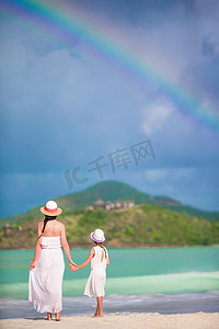 加勒比海滩上美丽的母亲和女儿，背景是惊人的彩虹