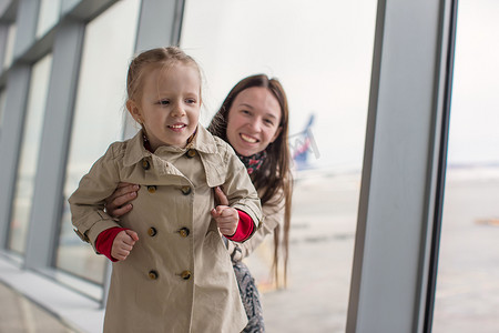母亲和小女儿靠近机场航站楼的窗户