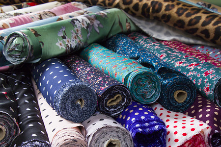 漂亮卷轴摄影照片_在商店货架上制作丝绸和布料，在市场上制作丝绸，多色和多图案纹理背景。