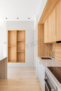 简单性摄影照片_沿着墙壁是一个带浅色木柜的现代厨房。