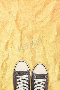 穿着运动鞋的脚站在战争沙漠的沙子上