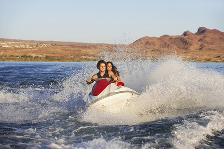 快乐的年轻白人夫妇在湖上骑水上摩托车