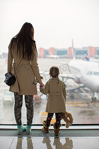 母亲和小女儿在机场航站楼望着窗外
