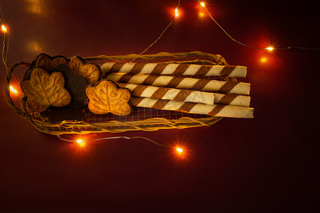 篮子里的饼干摄影照片_叶饼和篮子里放着奶油的管子，闪闪发光的圣诞灯