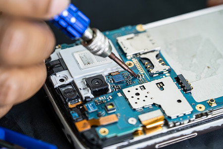 三维电路芯片摄影照片_技术人员用烙铁修理手机内部。