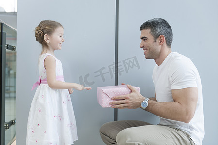 小女孩把礼物递给她的父亲