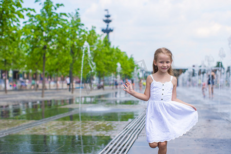 清爽一夏天摄影照片_阳光明媚的炎热日子里，快乐的小女孩在街头喷泉里玩得开心