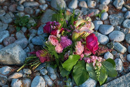 卵石和岩石背景上的婚礼花、新娘花束特写与玫瑰和百合
