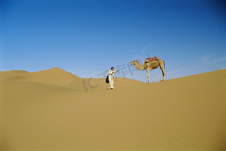 在户外骑着骆驼在沙漠中行走的女人（很远）