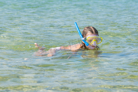 女孩带着面具和通气管漂浮在水面上