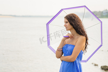 晨河背景上撑着雨伞站着的快乐小女孩