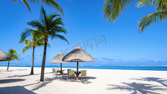 毛里求斯 Le Morne 海滩的热带海滩，带棕榈树和白沙蓝海的热带海滩，以及带雨伞、太阳椅和棕榈树下遮阳伞的沙滩床
