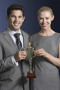 蓝色背景下拿着奖杯的年轻商人和女人的画像