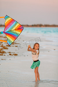 在热带海滩上放风筝的小奔跑女孩。