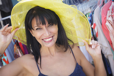 在市场上试戴黄色帽子的漂亮意大利女人