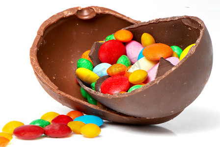 椭圆形的东西摄影照片_浅色背景中的复活节巧克力蛋和糖果