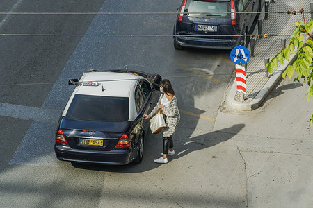 希腊塞萨洛尼基妇女戴着 covid-19 面具准备上出租车。