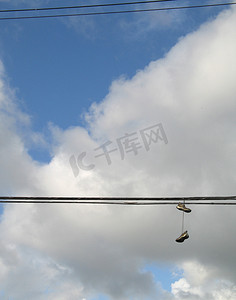 侧面鞋子摄影照片_挂在电线上的鞋子
