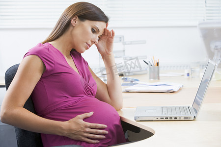 使用笔记本电脑工作的孕妇看起来压力很大