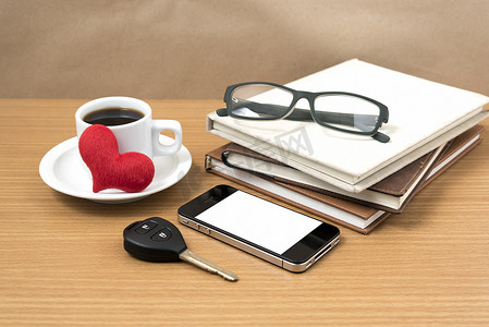 办公桌：咖啡和带车钥匙的电话、眼镜、一堆