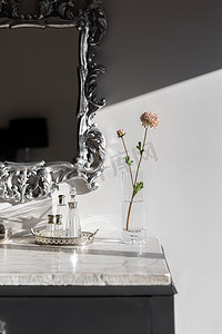 梳妆台的一部分，花瓶和花朵在白色大理石台面被阳光照亮。