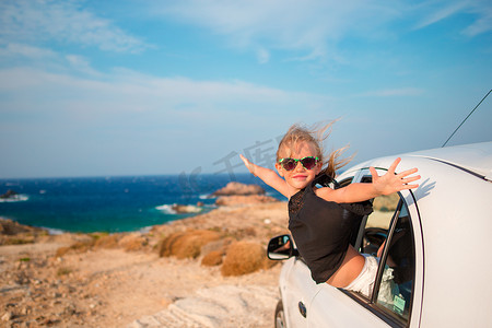 乘汽车旅行摄影照片_度假旅行的小女孩乘汽车背景美丽的风景