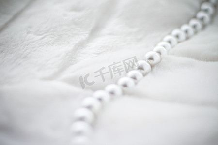 寒假摄影照片_寒假珠宝时尚，毛皮背景上的珍珠项链