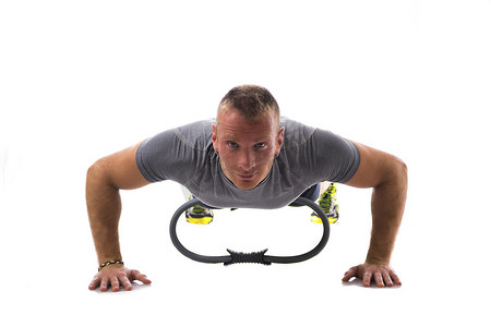 内裤男模腹肌写真摄影照片_年轻的肌肉男用普拉提环锻炼，与白色隔离
