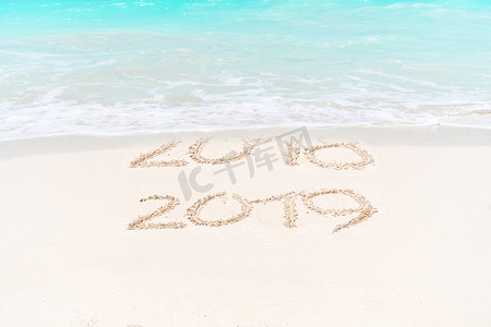 2018 年和 2019 年手写在沙滩上，背景是柔和的海浪
