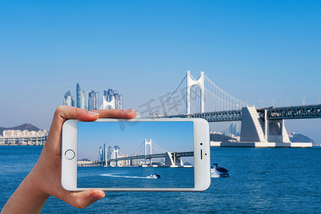 手持智能手机在广安大桥和 Haeu 拍照