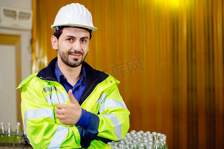 行服摄影照片_货运港口物流仓库中的肖像聪明拉丁工人自信地竖起大拇指，穿着安全服。
