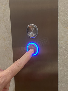 手指在蓝光下按下电梯按钮