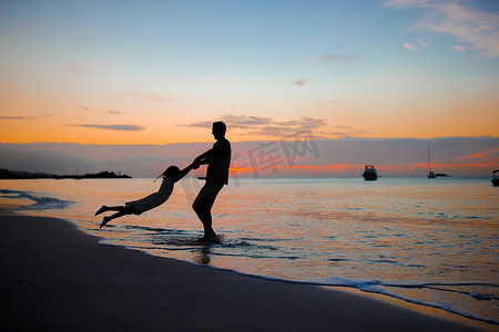 沙滩夕阳下的小女孩和快乐的父亲剪影