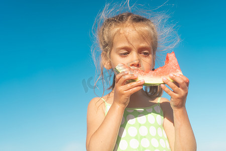 有趣的小女孩在海洋海滩吃西瓜阳光明媚的夏日。